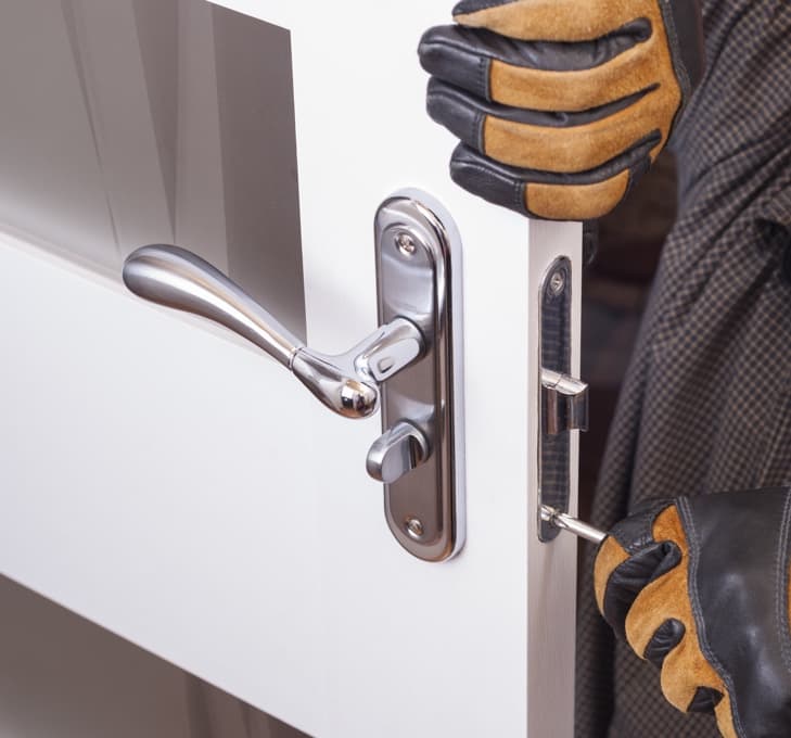Gloved hands working on stainless steel door latch.