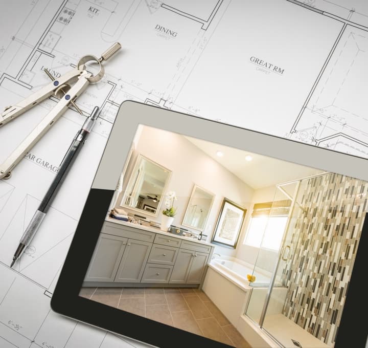Tablet with bath photo on top of house plans.